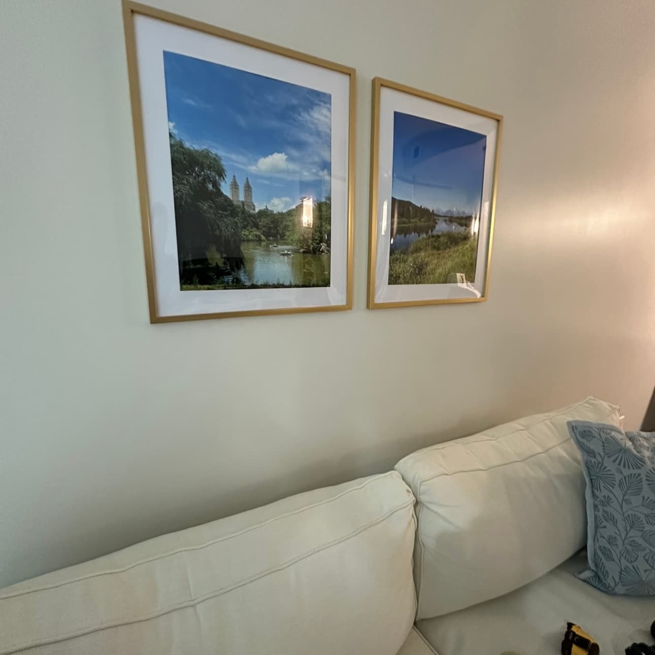 Two framed landscape prints hung level and evenly spaced above a sofa